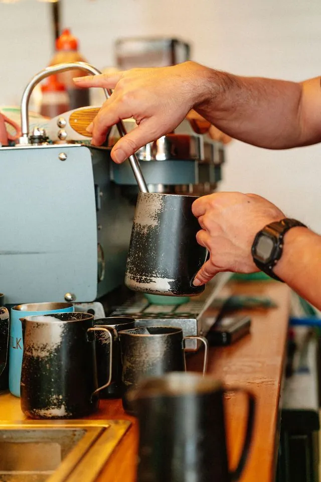 Barista pouring milk into a coffee